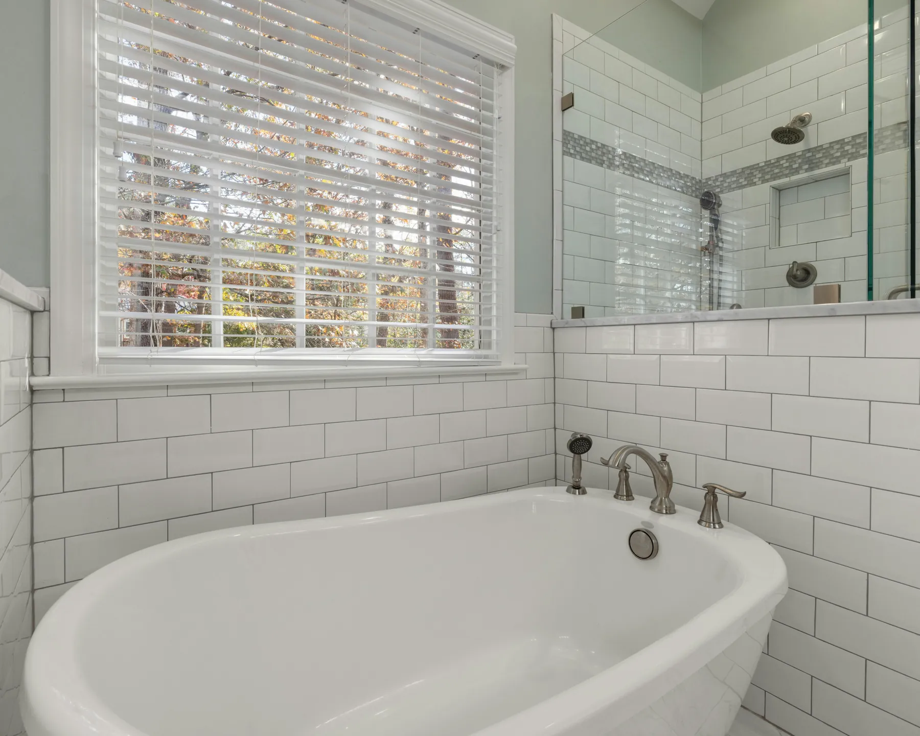 A bright bathroom with a soaking tub, subway tile, and a glass shower, used as a temporary visual example of a refreshed bathroom surface.